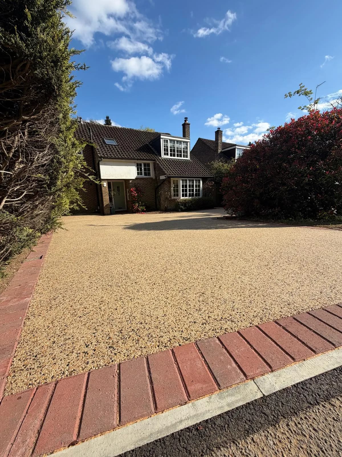 Resin driveway with a red-brick border outside a house